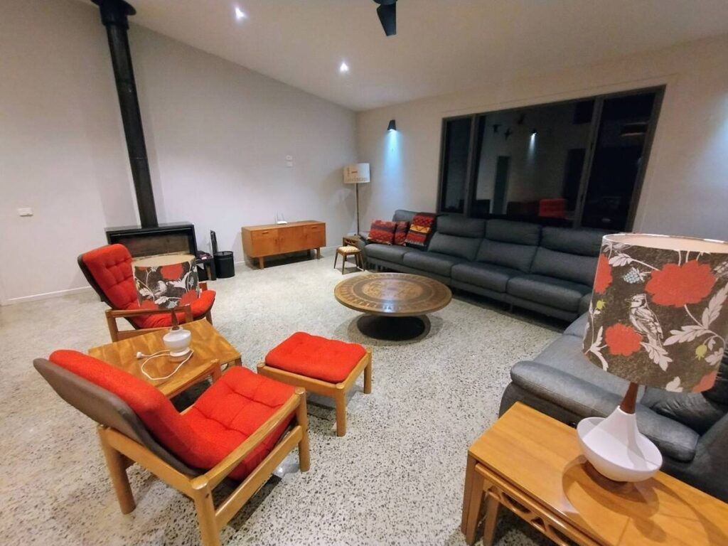 A modern living room featuring a gray sofa, red chairs, and a round wooden coffee table.