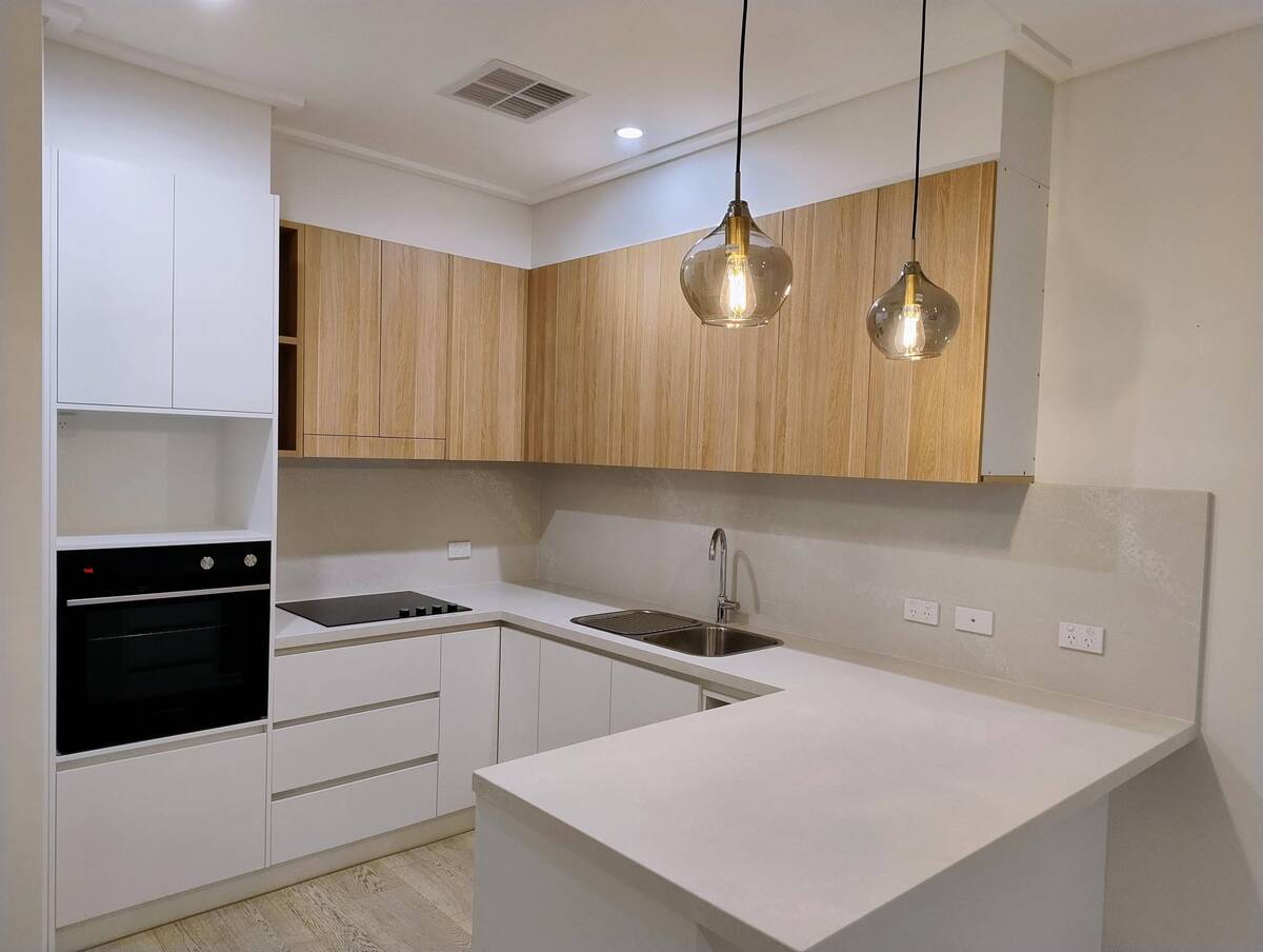 A modern kitchen with wooden cabinets and pendant lighting