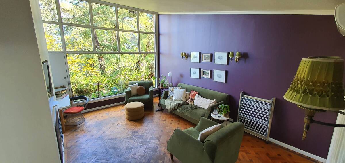 A bright living room with a green sofa and large windows.