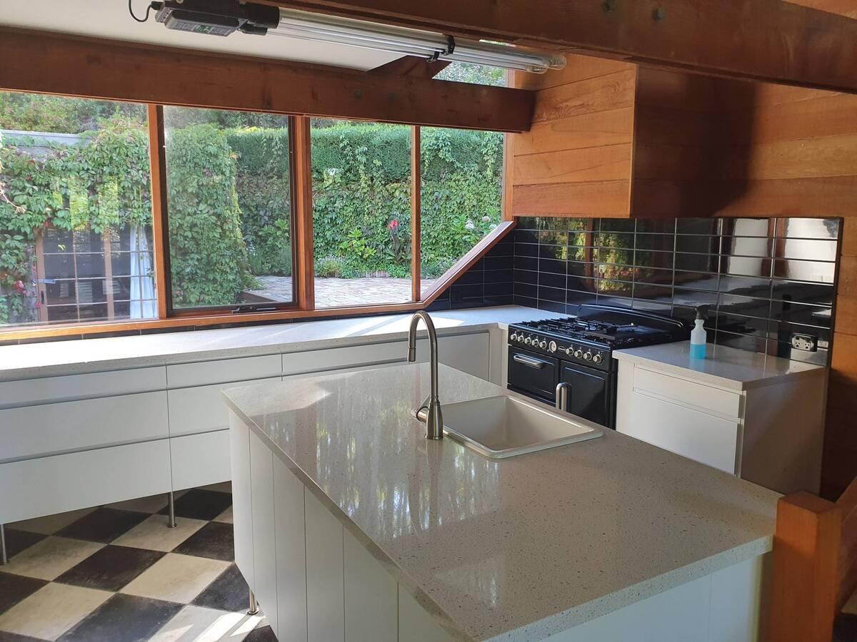 A modern kitchen with a central island and black tiled backsplash.